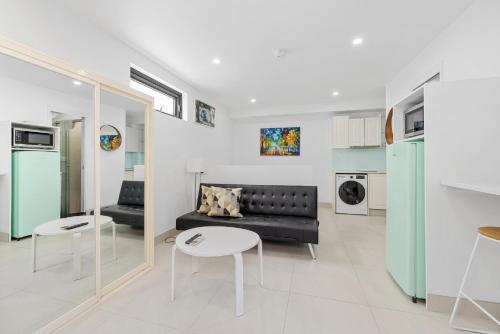 un soggiorno con divano nero e tavolo di Bright Studio Apartment in Surry Hills' Heart a Sydney