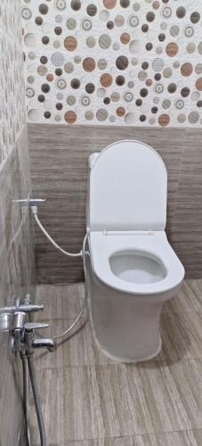 La salle de bains est pourvue de toilettes et d'un mur fleuri. dans l'établissement G GUEST HOUSE, à Gorakhpur