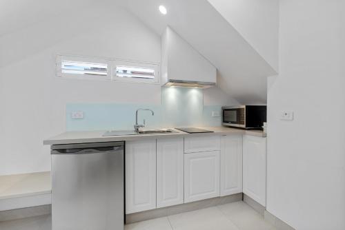 a white kitchen with a sink and a microwave at Modern & Bright Inner-City Studio Apartment in Sydney