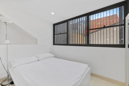 a white room with a white couch and a window at Modern & Bright Inner-City Studio Apartment in Sydney