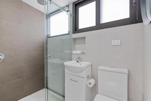 a bathroom with a toilet and a glass shower at Modern & Bright Inner-City Studio Apartment in Sydney