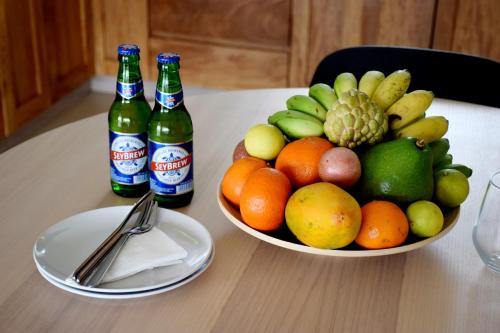 a bowl of fruit on a table with two bottles of beer at Lagati Self-Catering Seychelles in Mahe