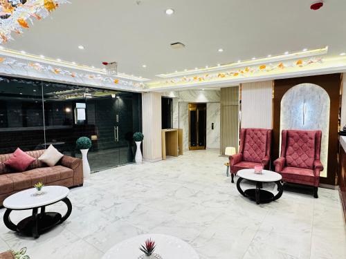 a lobby with two couches and two tables at Hotel IP Swarn near Anand Vihar Vaishali Ghaziabad in Ghaziabad