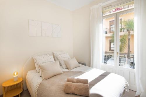 une chambre blanche avec un lit et une fenêtre dans l'établissement REPUBLIQUE - Somptueux 2 pièces - 50 mètres de Monaco, à Beausoleil