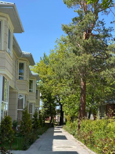 a house with a tree on the side of a street at Raduga West 'Pearl' Apartment in Koshkolʼ
