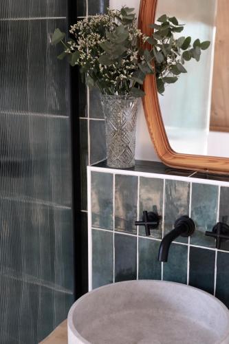 La salle de bains est pourvue d'un lavabo, d'un miroir et d'un vase fleuri. dans l'établissement Racine lodges, à Saint-Léon-sur-Vézère