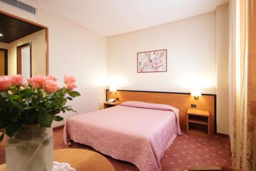 une chambre d'hôtel avec un lit et un vase de fleurs dans l'établissement Hotel Executive Meeting & Events, à Udine