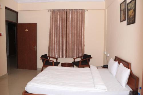 a bedroom with a bed with two chairs and a window at DWARKA KUNJ in Vrindāvan