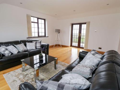 a living room with a black leather couch and a table at Doonalton House in Carrowmably