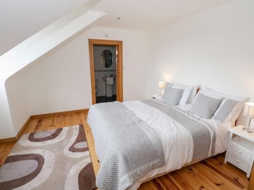 een witte slaapkamer met een groot bed en een houten vloer bij Doonalton House 