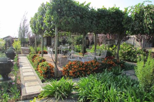 a garden with a table and chairs and flowers at Oudam Overnight Accomodation in Bloemfontein