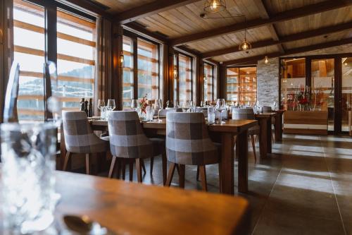 a restaurant with wooden tables and chairs and windows at Hotel Lukov Dom in Mislinja