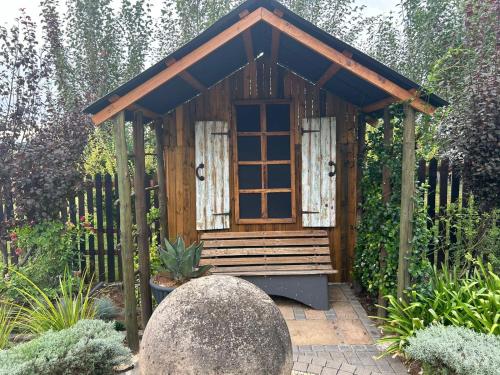 a small shed with a bench in a garden at Oudam Overnight Accomodation in Bloemfontein