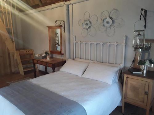 a bedroom with a large white bed and a table at Oudam Overnight Accomodation in Bloemfontein