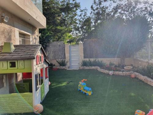 a backyard with a toy house and a playground at Lavi La in Modi'in-Maccabim-Re'ut