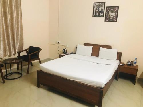 a bedroom with a bed with a chair and a desk at DWARKA KUNJ in Vrindāvan