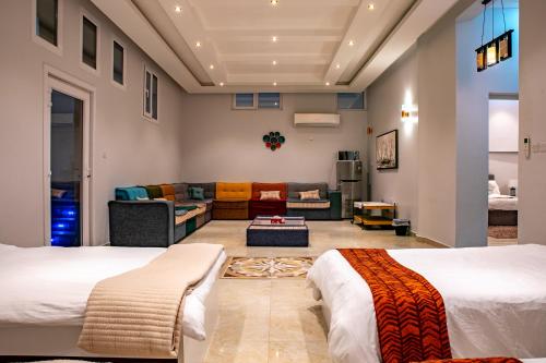 een woonkamer met 2 bedden en een bank bij Elegant Garden & 2Living Areas, 2 Bed Rooms for 6 Guests in Umm al ‘Amad
