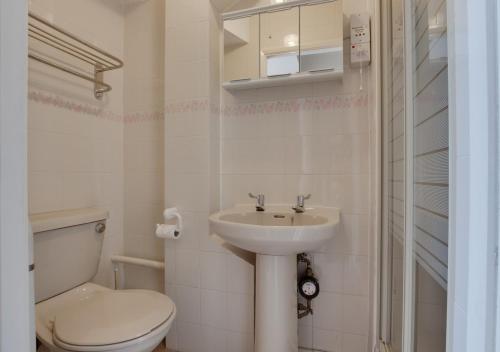 a white bathroom with a toilet and a sink at 3A Strandways in Saundersfoot