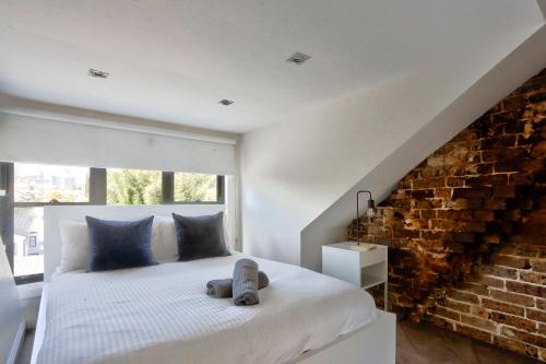 1 dormitorio con cama blanca y pared de ladrillo en Spacious 3 Bedroom House Glebe with 2 E-Bikes Included en Sídney