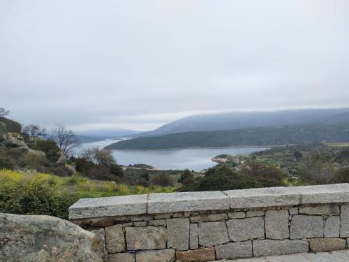 a stone wall with a view of a lake at Alojamientos El Castillo in El Berrueco