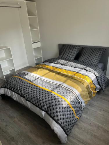 a bedroom with a bed with a black and yellow comforter at Bel appartement de 60 m2 in Rosières-près-Troyes