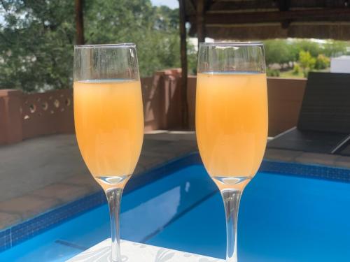due bicchieri da champagne seduti accanto alla piscina di Victoria Oaks Beaufort West Guesthouse a Beaufort West