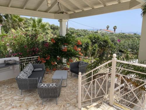 a patio with chairs and a table and some flowers at Luxurious Villa in Peloponnese with Swimming Pool in Kamária