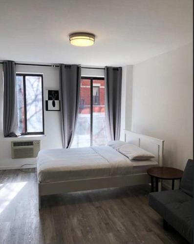 ein Schlafzimmer mit einem Bett, einem Sofa und Fenstern in der Unterkunft Cozy Studio! Upper East Side! in New York