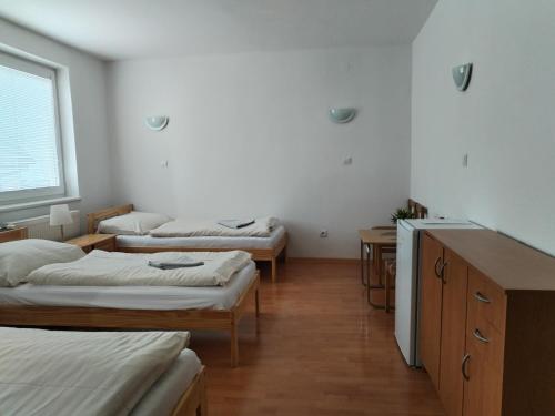 a room with three beds and a window at Turistická ubytovňa Hornád in Spišské Tomášovce
