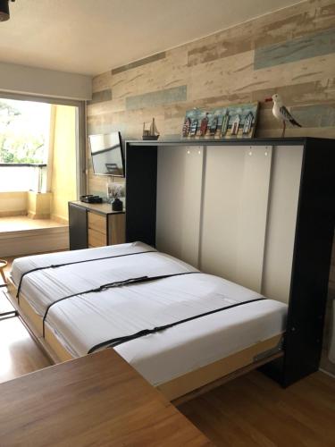 - une chambre avec un lit avec une étagère sur le mur dans l'établissement Studio Bords de plage, à Saint-Jean-de-Monts