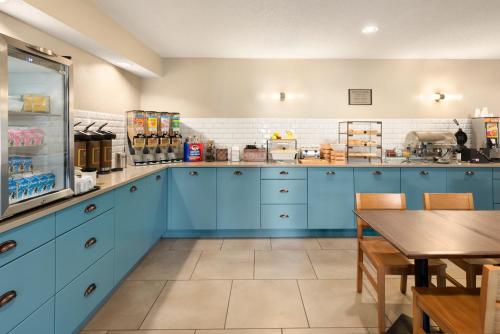 a kitchen with blue cabinets and a wooden table at Country Inn & Suites by Radisson, Chippewa Falls, WI in Chippewa Falls