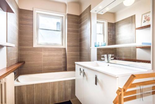 uma casa de banho com um lavatório, uma banheira e uma janela. em Saint-Jean de Luz, Centre, Maison 8 couchages - classée 3* em Sainte-Barbe