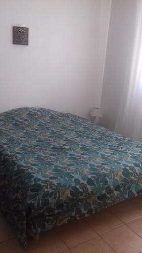 Una cama en una habitación con una manta. en Maison avec piscine à Aigues Mortes, en Le Grau-du-Roi