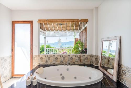 a bath tub in a room with a large window at Soul Villas by The Beach - Phuket in Panwa Beach