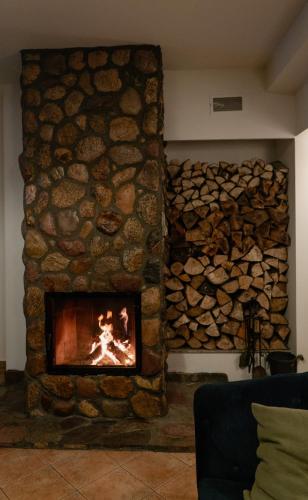 a stone fireplace in a room with a pile of logs at Ranczo Brusno in Połczyn-Zdrój