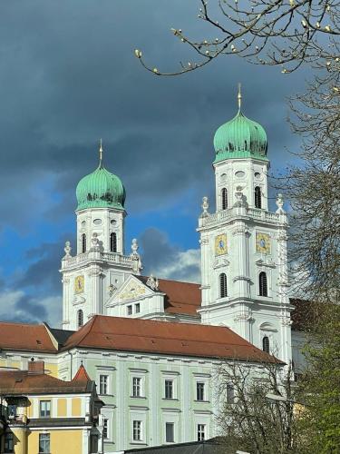 a large white building with two towers with green roofs at ZumGlückFrei in Passau