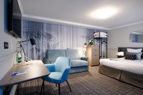 um quarto de hotel com uma cama e uma cadeira azul em Hotel Vacances Bleues Provinces Opera em Paris