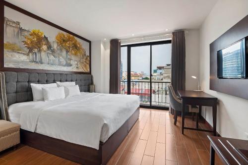 a bedroom with a bed and a desk and a window at 22Land Residence Hotel & Spa Hanoi in Hanoi