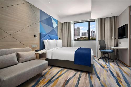 Holiday Inn Express Singapore Serangoon, an IHG Hotel في سنغافورة: غرفه فندقيه بسرير واريكه