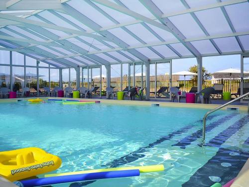 une piscine intérieure avec un grand plafond en verre dans l'établissement Les les Anglo Normandes holiday resort Portbail, à Portbail