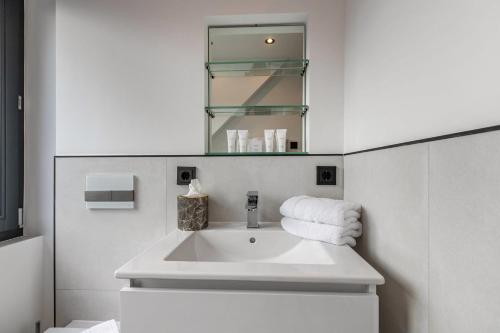 a white bathroom with a sink and a mirror at Horst Wai Hues in Westerland (Sylt)