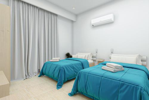 two beds in a white room with blue sheets at Caretta Paradise Resort & WaterPark in Tragaki