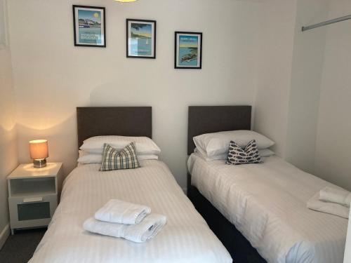 two twin beds in a bedroom with a lamp and pictures on the wall at Brixham Cottage with views in Brixham