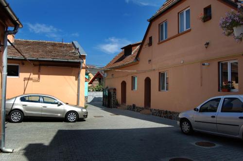 two cars parked in a parking lot between two buildings at Pensiunea Casa Sighisoreana in Sighişoara