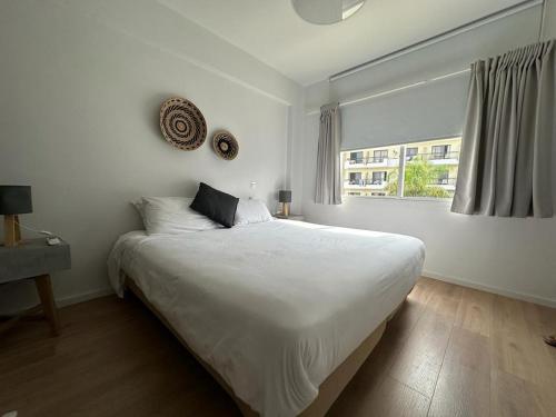 een witte slaapkamer met een groot bed en een raam bij KSQUARED in Protaras
