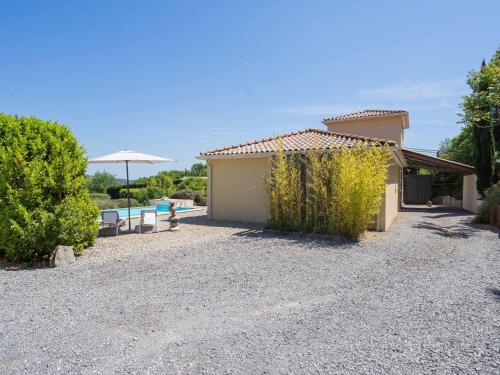 a gravel driveway with a house and an umbrella at Mesmerising villa in Les Vans with private pool in Les Vans