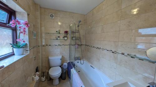 a bathroom with a tub and a toilet and a sink at Relaxing 3 Bedroom Norwich Haven in Norwich