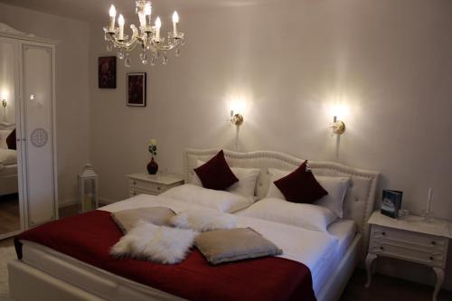 Un dormitorio con una cama blanca con almohadas y una lámpara de araña. en ZumGlückFrei en Passau