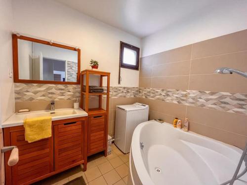 een badkamer met een bad, een wastafel en een spiegel bij Appartement tout confort avec vue in Saint-Denis