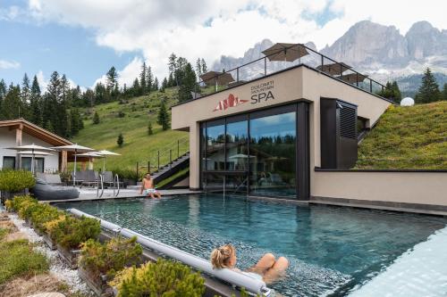 Una donna sdraiata in una piscina in un resort di Moseralm Dolomiti Spa Resort a Nova Levante